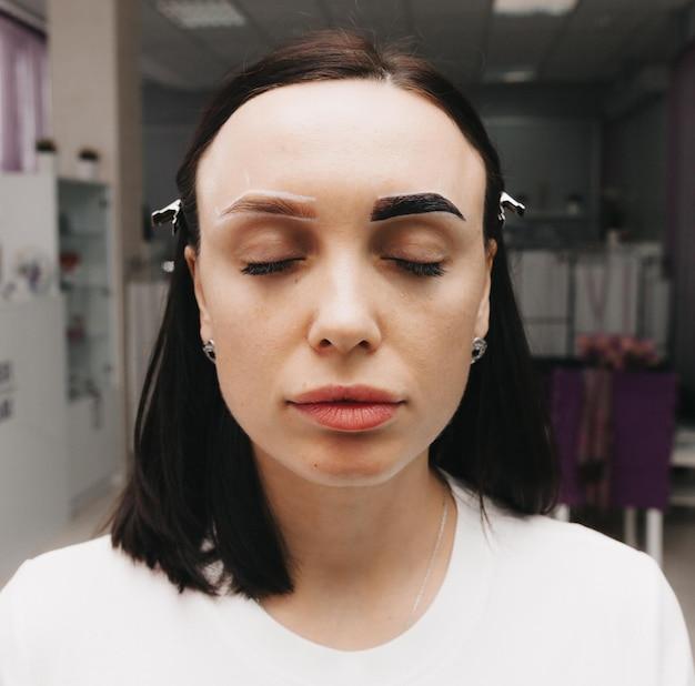 Woman with closed eyes undergoing eyebrow beauty treatment